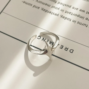 Close-up of minimalist silver star ring on a white card with natural light shadows