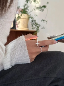 Close-up of S925 silver star and wavy stackable rings worn on a hand in a cozy setting