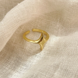 Macro shot of gold star minimalist ring on a textured fabric background