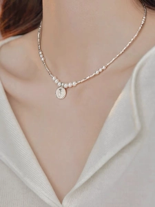 Macro detail of S925 silver necklace with round pearls and a rose embossed pendant