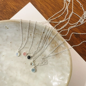 Detailed macro view of S925 silver necklaces with colorful crystal pendants in a ceramic tray