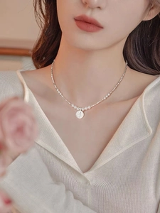 Close-up of French S925 silver irregular beads and round pearl necklace with coin pendant