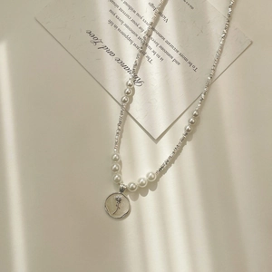 Detail view of pearl and crushed silver necklace with an elegant rose embossed pendant