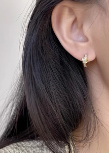 Close-up of gold knotted hoop earring with baguette-cut zircons worn by model