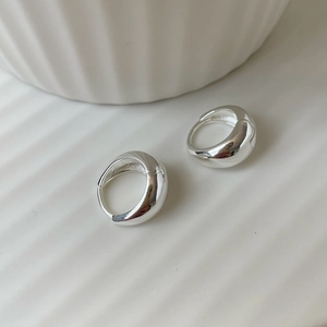 Close-up of minimalist S925 sterling silver oval hoop earrings on a ceramic tray