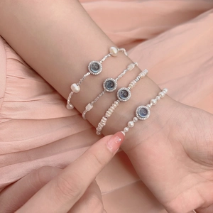 Close-up of S925 silver pearl bracelet set with blue gemstone on soft pink fabric