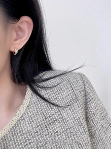 Close-up of elegant gold knot hoop earrings with sparkling micro-inlaid stones on model