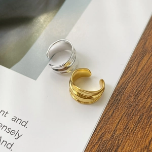 Detail view of irregular gold and silver ear cuffs with modern ripple fold texture