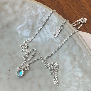 Detail showing S925 sterling silver stamp and blue crystal stone on minimalist necklace