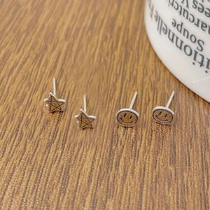 Gros plan de boucles d'oreilles en argent S925 étoile et smiley sur bois sombre