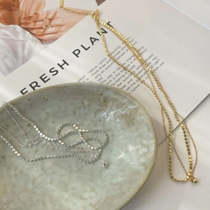 Detail view of gold and silver minimalist disc necklaces on a decorative ceramic plate