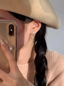 Gros plan de boucles d'oreilles nœud papillon en argent sterling S925 sur l'oreille