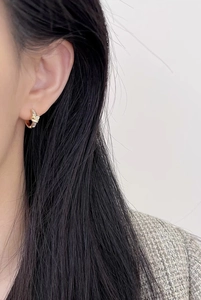 Detailed view of gold knotted hoop earrings with micro-inlaid diamonds on model ear