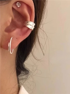 Close-up of irregular textured silver ear cuff and double hoop earrings set on ear