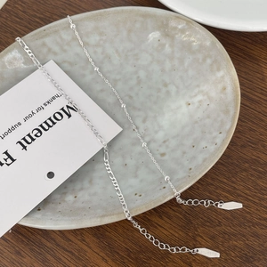 Detail of 925 sterling silver beaded and Figaro chain necklaces on a ceramic tray