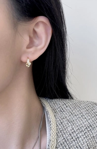 Close-up of golden S925 silver knot earrings with pavé square cubic zirconia stones
