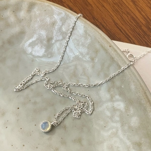 Close-up of minimalist S925 sterling silver necklace with glowing round moonstone pendant