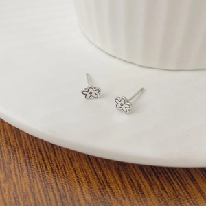 Vue macro de boucles d'oreilles fleurs en argent avec émail sur plat céramique