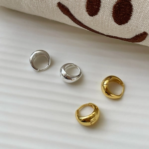 Detailed view of polished gold and silver hoop earrings with a thick streamlined design