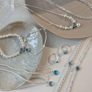 Macro shot of S925 silver pearl necklaces with aquamarine gemstones and layered bracelets