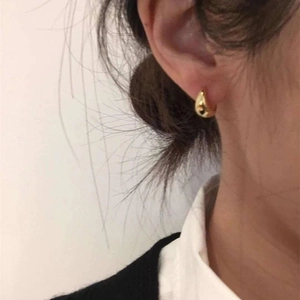 Close-up of elegant gold water drop earrings with a polished mirror finish on a model
