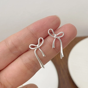Gros plan de boucles d'oreilles nœud en argent S925 montrant la taille réelle