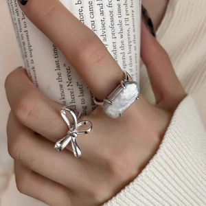 Detail of s925 silver bow ring and large baroque pearl ring on hand with coffee cup