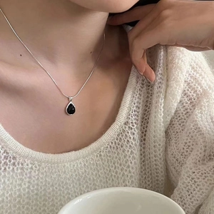Close-up of S925 sterling silver snake chain necklace with black teardrop pendant on a model