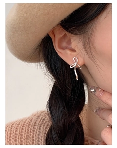 Gros plan de boucles d'oreilles nœud en argent sterling S925 portées par un mannequin