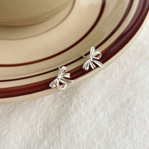 Élégantes boucles d'oreilles nœud en argent 925 présentées sur une assiette en céramique