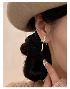 Gros plan sur une puce d'oreille nœud en argent poli portée avec élégance par un mannequin