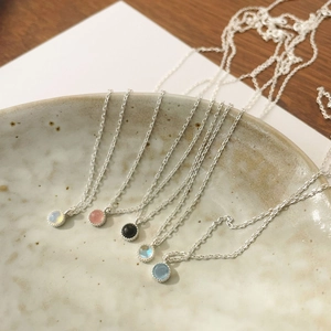 Close-up of five minimalist S925 sterling silver necklaces with colorful crystal pendants