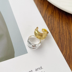 Detail showing irregular wavy texture of gold and silver ear cuffs on white magazine