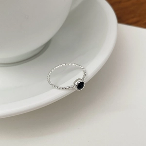 Détail d'une bague tressée en argent S925 avec une pierre noire sertie en couronne