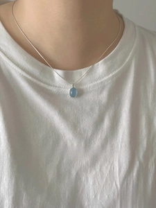 Close-up of an oval blue moonstone pendant on a sleek silver snake chain necklace
