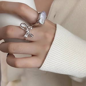 Detail shot of a 925 sterling silver bow ring and a baroque pearl ring on a model hand