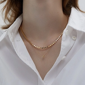 Close-up of layered S925 sterling silver gold necklace featuring a solid sphere pendant