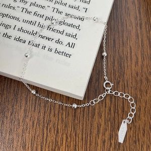 Detail of 925 sterling silver beaded bracelet with adjustable chain on a wooden desk