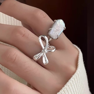 Close-up of 925 silver bow ring with baroque pearl worn on finger over knit sweater