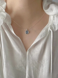 Close-up of S925 sterling silver necklace with oval blue moonstone on silk fabric