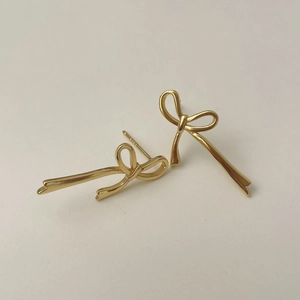 Détail macro de boucles d'oreilles ruban doré montrant le poinçon en argent S925