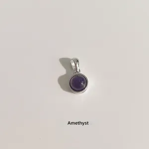 Gros plan d'un pendentif en améthyste ronde polie monté sur de l'argent minimaliste