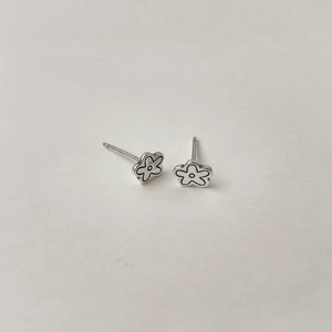 Gros plan sur les boucles d'oreilles fleurs en argent S925 avec des contours noirs détaillés