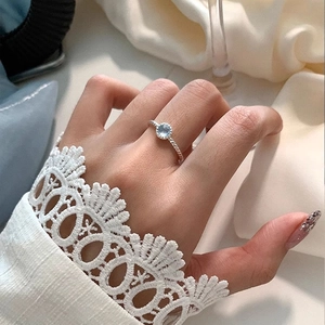 Gros plan d'une bague torsadée en argent S925 avec cristal bleu clair sur la main