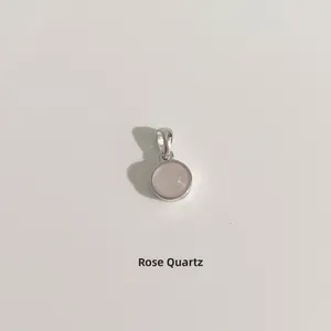 Gros plan d'un pendentif en quartz rose rond avec une bélière en métal argenté poli
