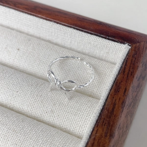 Vue macro de la bague nœud en argent S925 avec texture torsadée en boîte cadeau