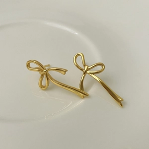 Détail macro des boucles d'oreilles nœud minimalistes en argent sterling doré poli