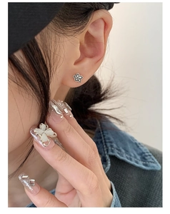 Détail d'une boucle d'oreille fleur argentée minimaliste portée par un mannequin réel