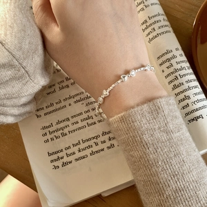 Détail du bracelet en argent S925 avec maillons en cœur sur le poignet d'une femme