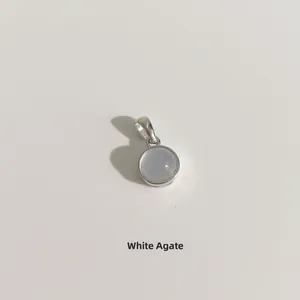 Détail macro d'un pendentif rond en agate blanche avec monture en argent poli